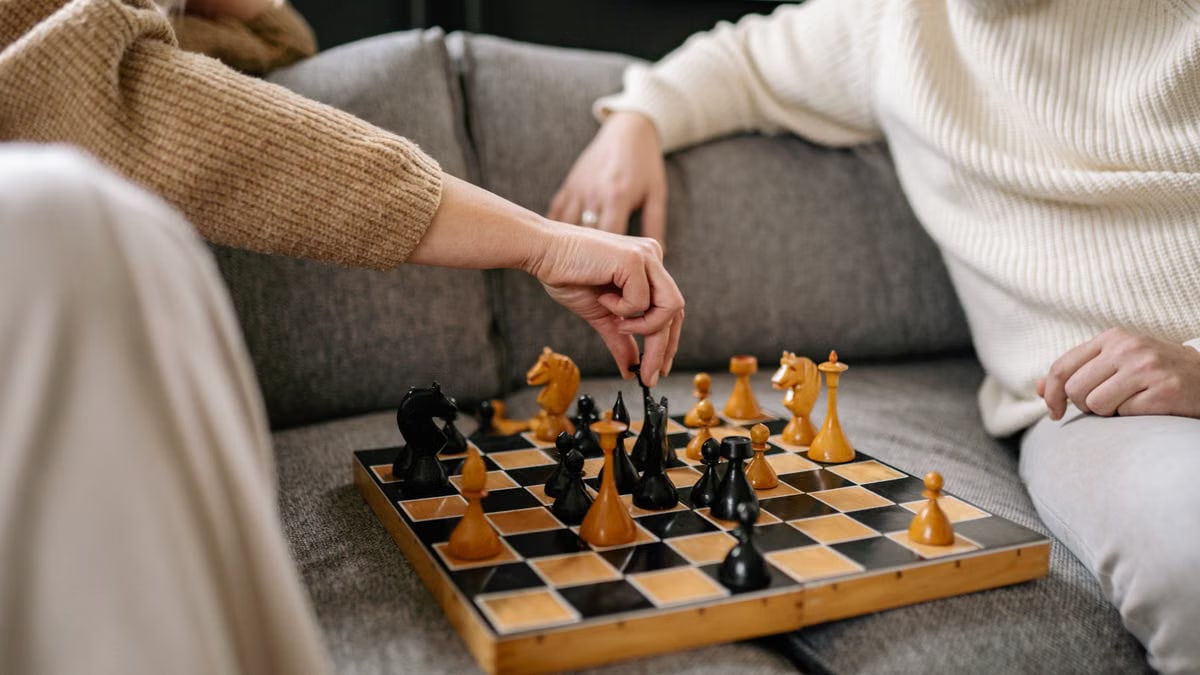 Close-up of a senior couple playing a game of chess on a cozy sofa indoors.